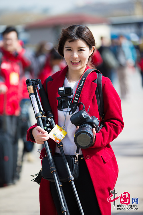 2016年兩會，人民大會大堂前，一位笑容燦爛的紅衣女記者正步入大會堂。中國網 鄭亮 攝